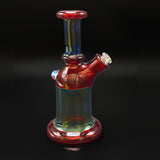 Three-quarter view of the hand blown tube, red at the lip and foot with blue and green through the body