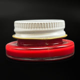 Empty 1 threaded glass jar in cherry red with its white metal screw lid on, side view