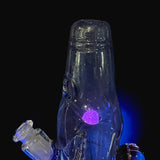 The Dabune bottle photographed under a blacklight, the Lucy UV marble glowing violet inside the body