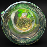 Looking down through the mouthpiece of the mini tube at a cluster of gold-toned bubbles
