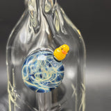 Close-up of the duck marble, a yellow glass duck perched on blue and cream glass
